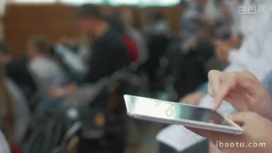 医学讲座会议或研讨会期间，妇女在礼堂里用平板电脑打字的特写镜头